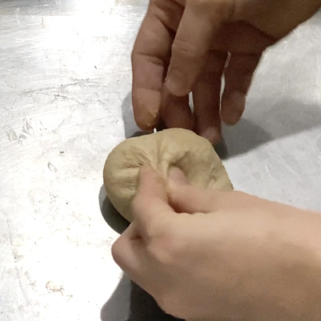 Hands pinching dough together to help form a ball
